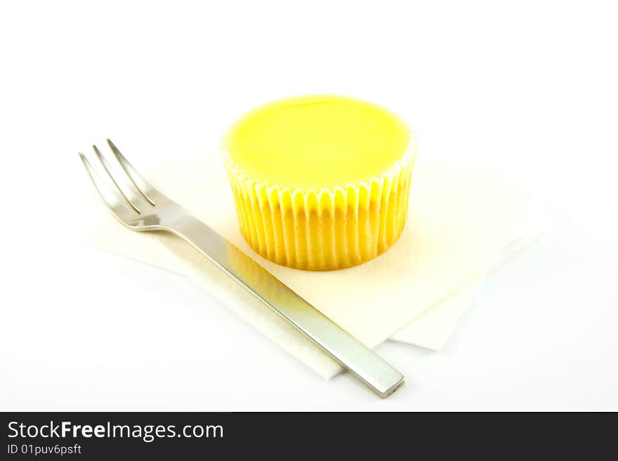 Delicious looking cup cake resting on two white napkins with a fork on a plain background