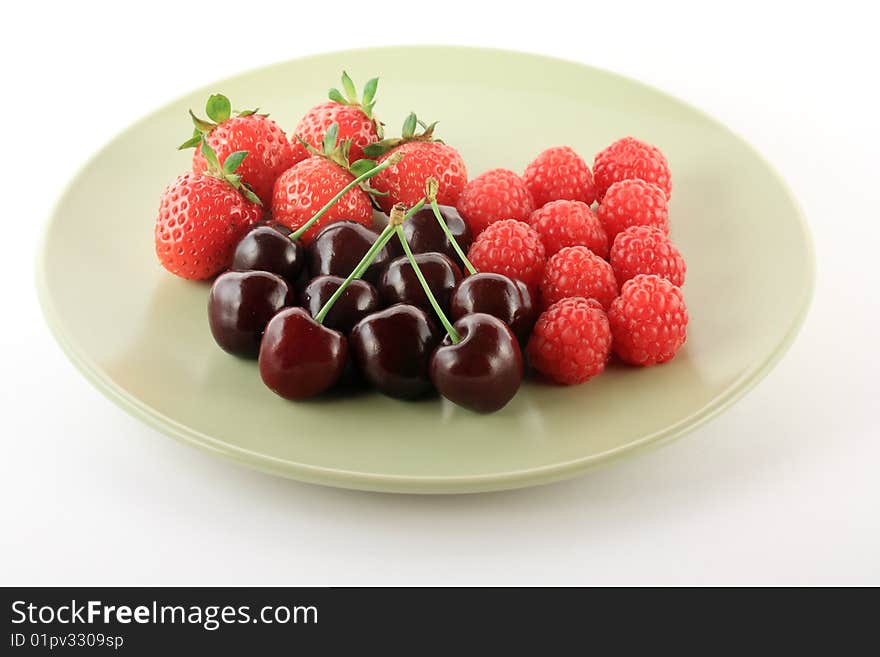 Cherry, raspberry and strawberry on a light green plate. Cherry, raspberry and strawberry on a light green plate