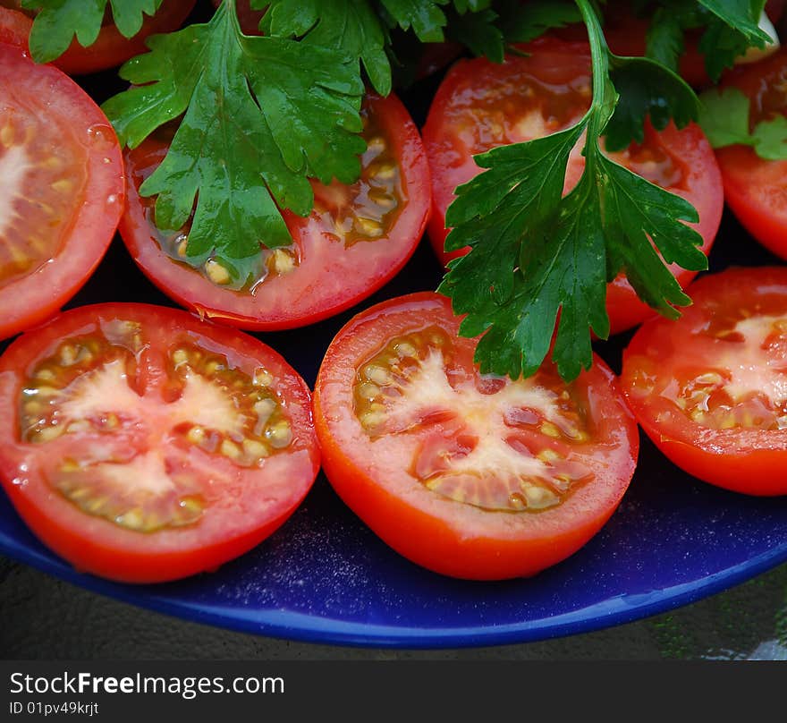 Halves of tomatoes on a dark blue dish. Halves of tomatoes on a dark blue dish