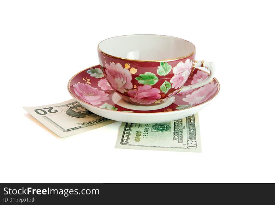 Tea cup and saucer on on twenty dollar bills isolated. Tea cup and saucer on on twenty dollar bills isolated