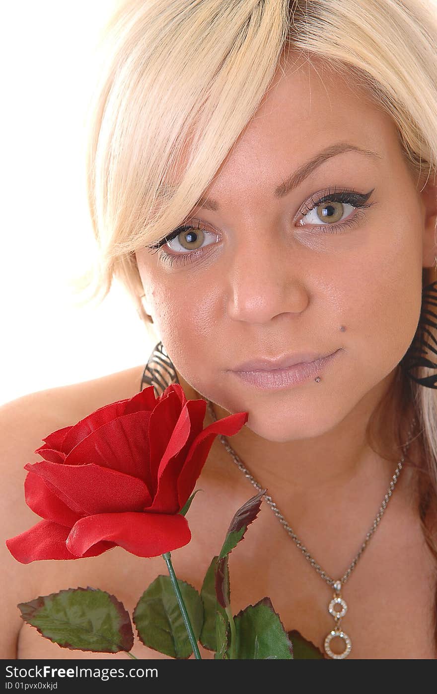 Very lovely young blond girl with an red rose in her hand and a diamond necklace around the neck in a portrait shot in close up. Very lovely young blond girl with an red rose in her hand and a diamond necklace around the neck in a portrait shot in close up.