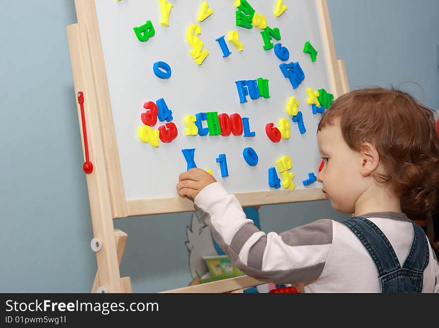 Little boy playing magnetic letters on whiteboard. Little boy playing magnetic letters on whiteboard