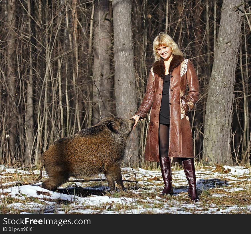 Blonde girl with wild boar at the forest