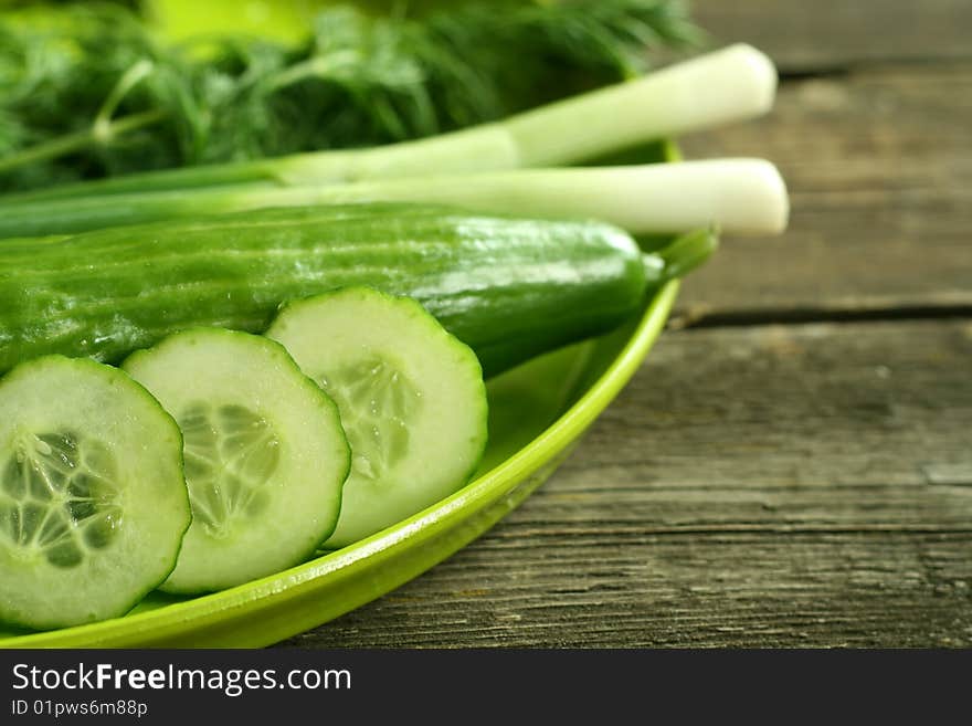 Cucumbers onions and fennel on a green plate on wooden