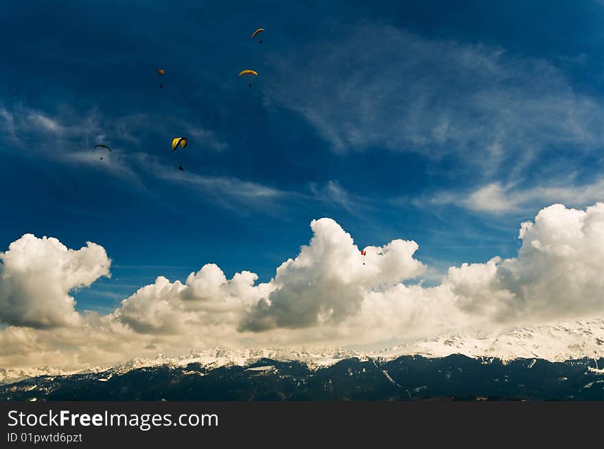 The photo of the group of parachutists living in the clouds above the mountains in Alps. Made from the parachutists take-off point. The photo of the group of parachutists living in the clouds above the mountains in Alps. Made from the parachutists take-off point.