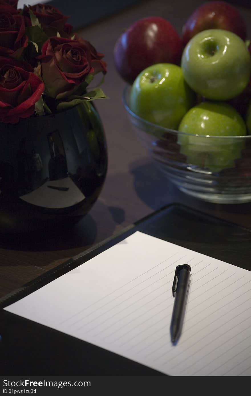 A blank corporate display book with a bowl of apples and red roses.