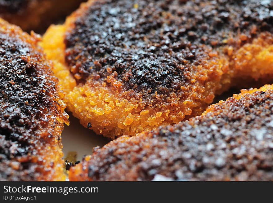 Slightly burnt chicken cutlets on the plate. Narrow depth of field. Slightly burnt chicken cutlets on the plate. Narrow depth of field.