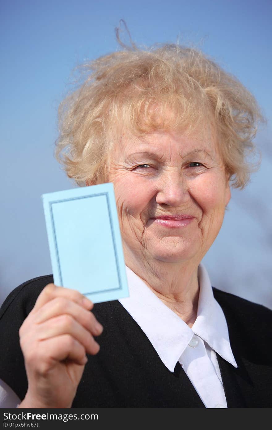 Aged woman holds card in hand on sky