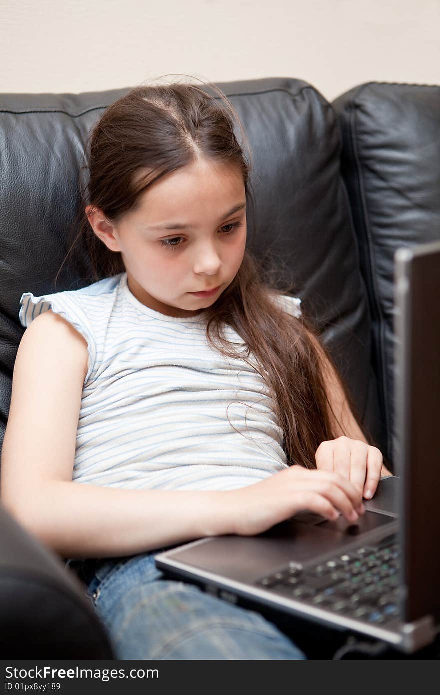 Girl sits on a sofa with the laptop in a lap