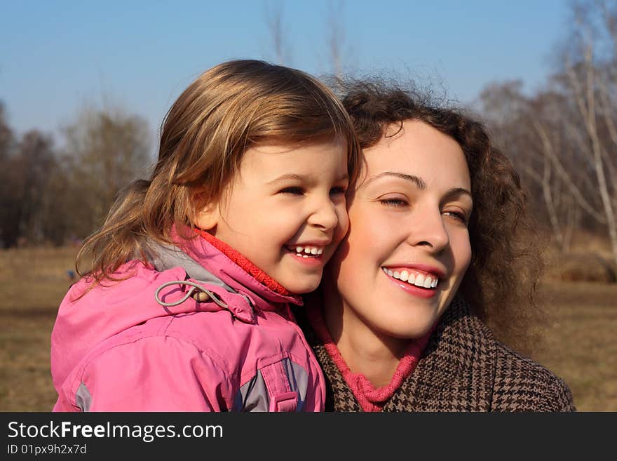 Mother with little daughter on hands outdoor in spring