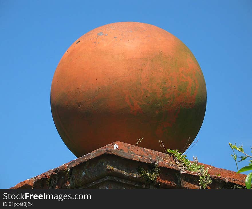 Sphere of orange brick on a wall with blue sky background