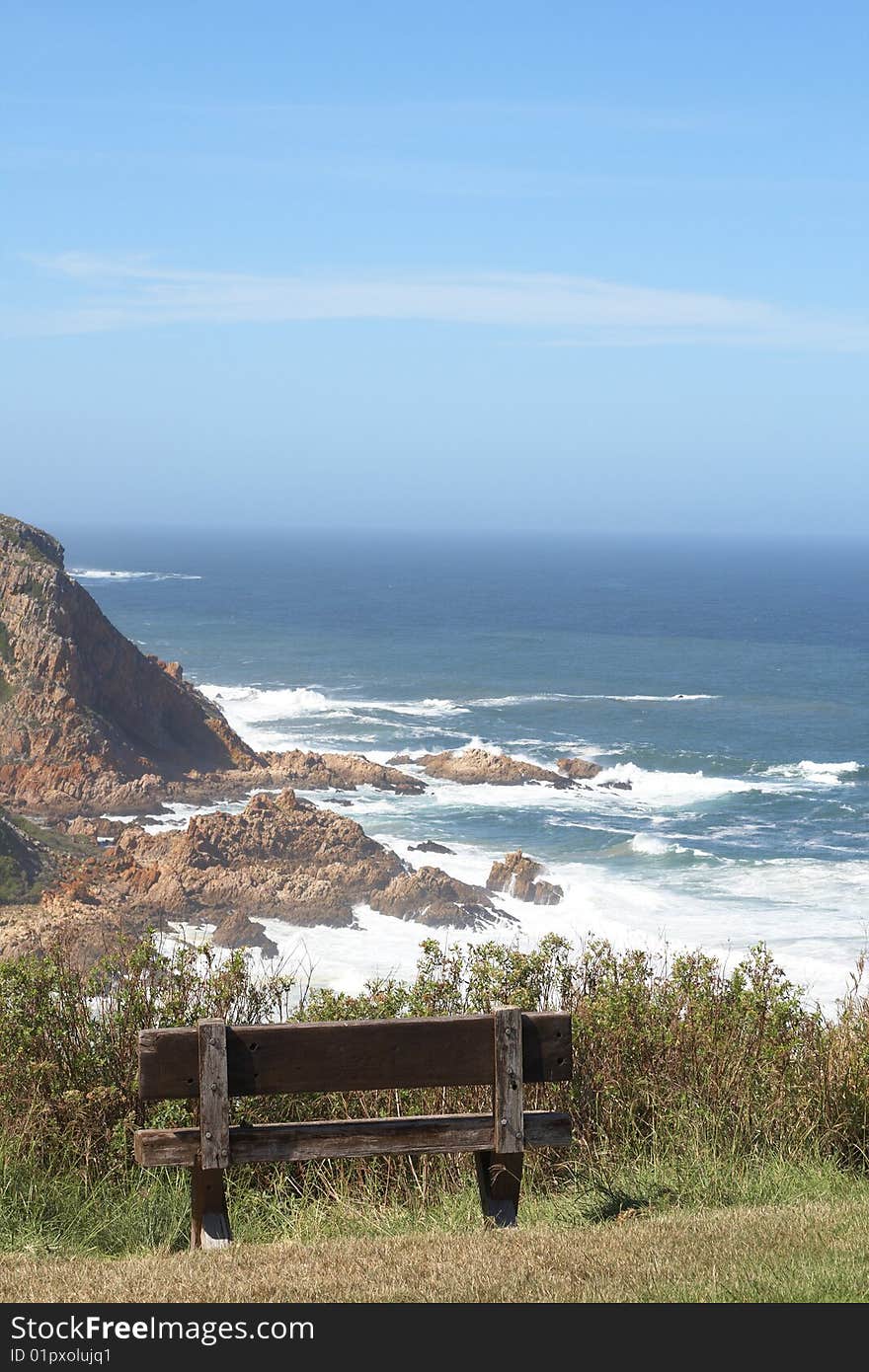 Ocean landscape with mountains and an empty wooden bench on a beautiful summer day