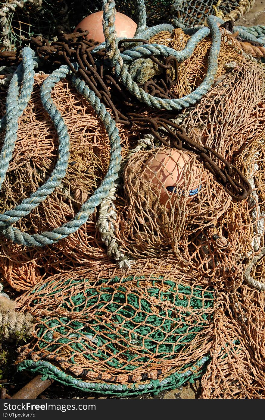 Fishing nets, ropes, chain and buoys lying in sunlight. Fishing nets, ropes, chain and buoys lying in sunlight