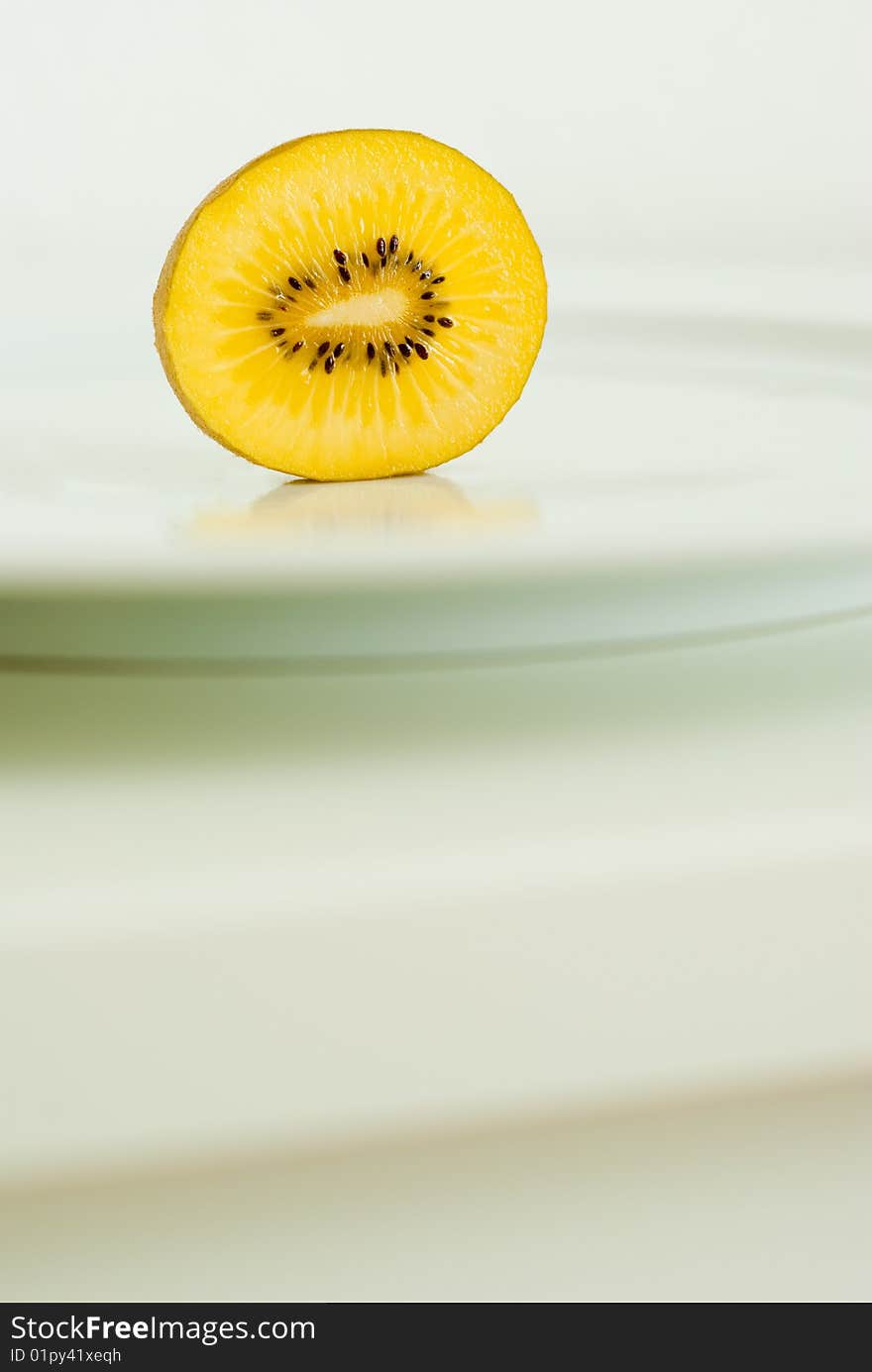 A sliced golden yellow Kiwi on a plate. A sliced golden yellow Kiwi on a plate.