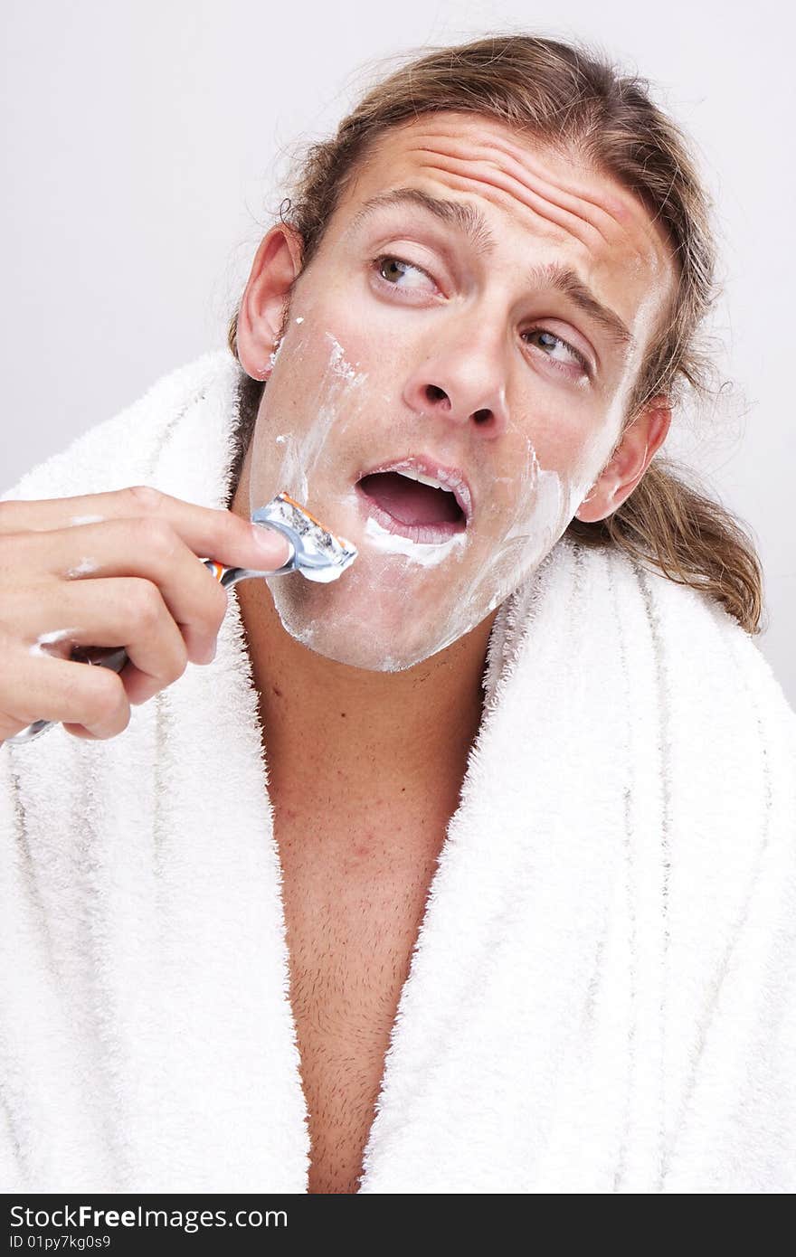 Portrait of a young handsome man shaving as part of his morning routine. Portrait of a young handsome man shaving as part of his morning routine.