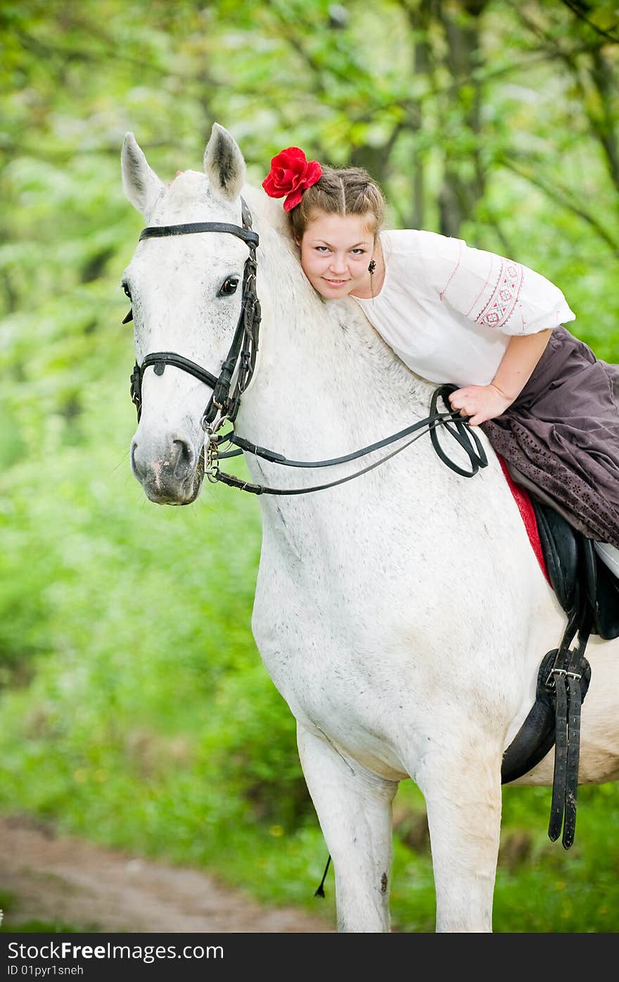 Beautiful girl riding white horse in the forest