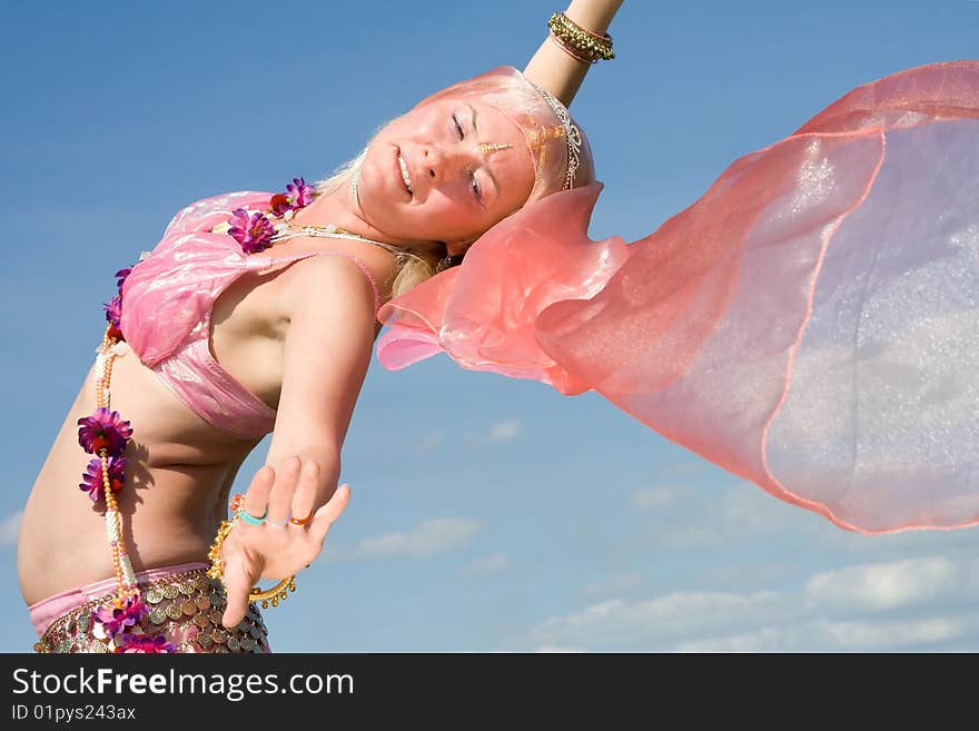 A woman in pink asian dress dancing and a blue sky. A woman in pink asian dress dancing and a blue sky