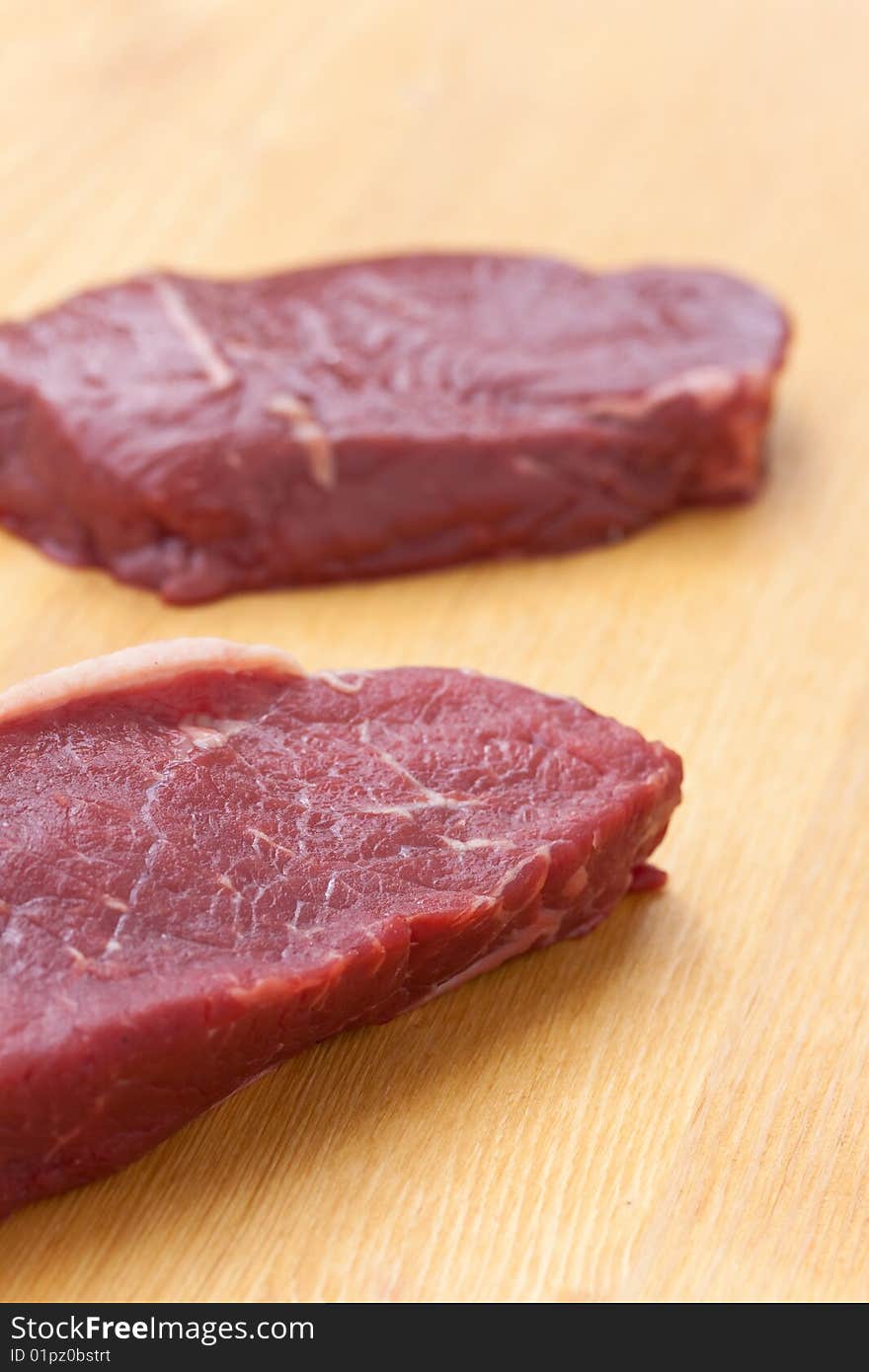 Uncooked Steaks On Wooden Cutting Board