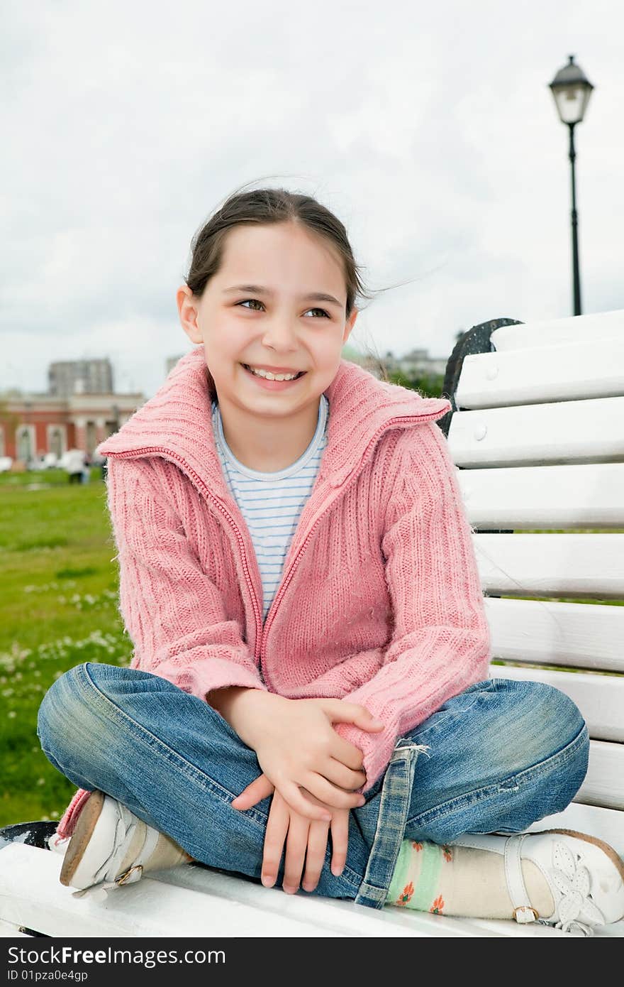 Girl sits on a white bench in park. Girl sits on a white bench in park