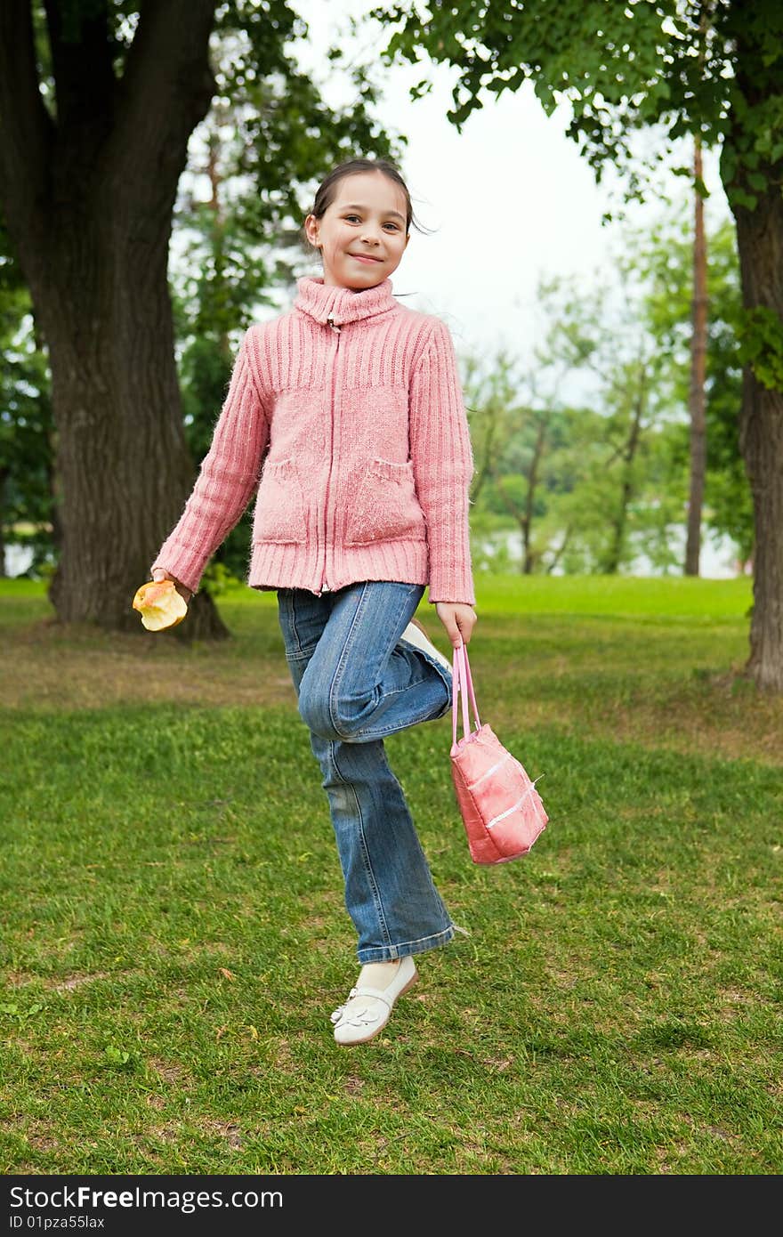 Girl jumps on a green grass against trees