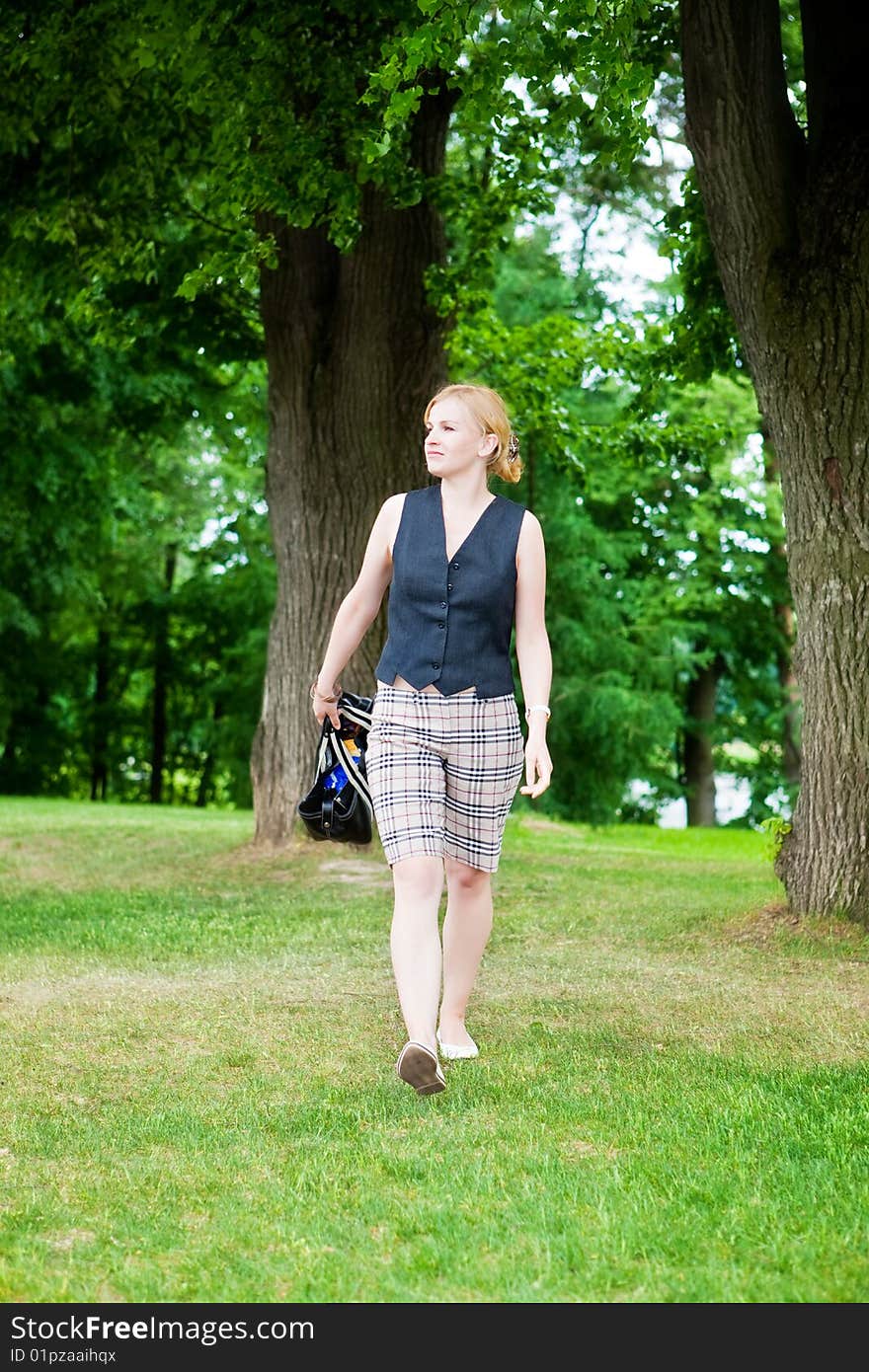 Beautiful woman walks on a green grass in park