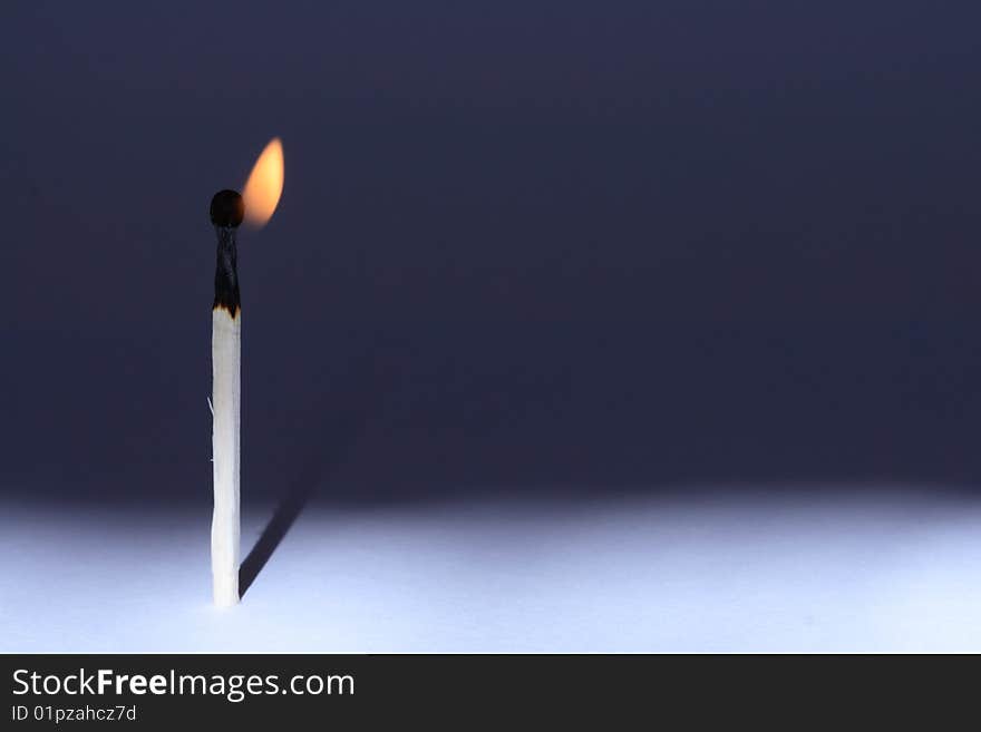 A lone burning match standing on gradient background. Horizontal image