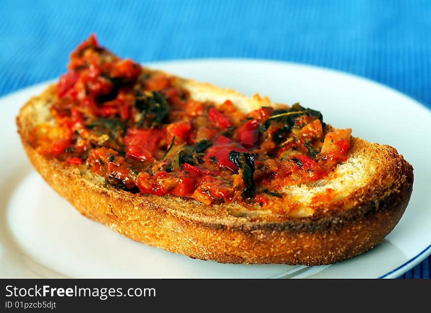 Toast with grilled tomato and herbs, white plate and blue background, shallow DOF