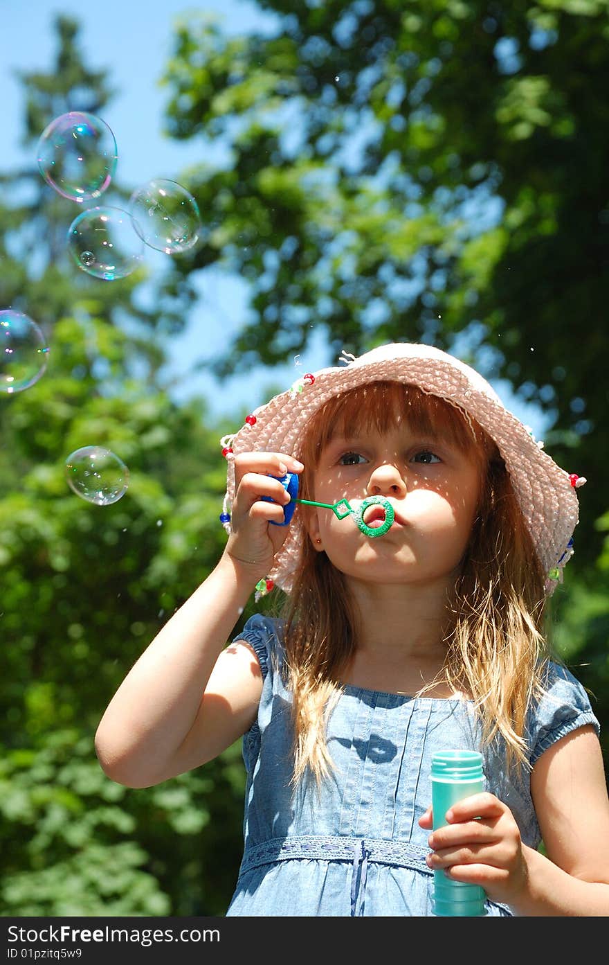 Adorable little girl playing with a bubble wand. Vertical.