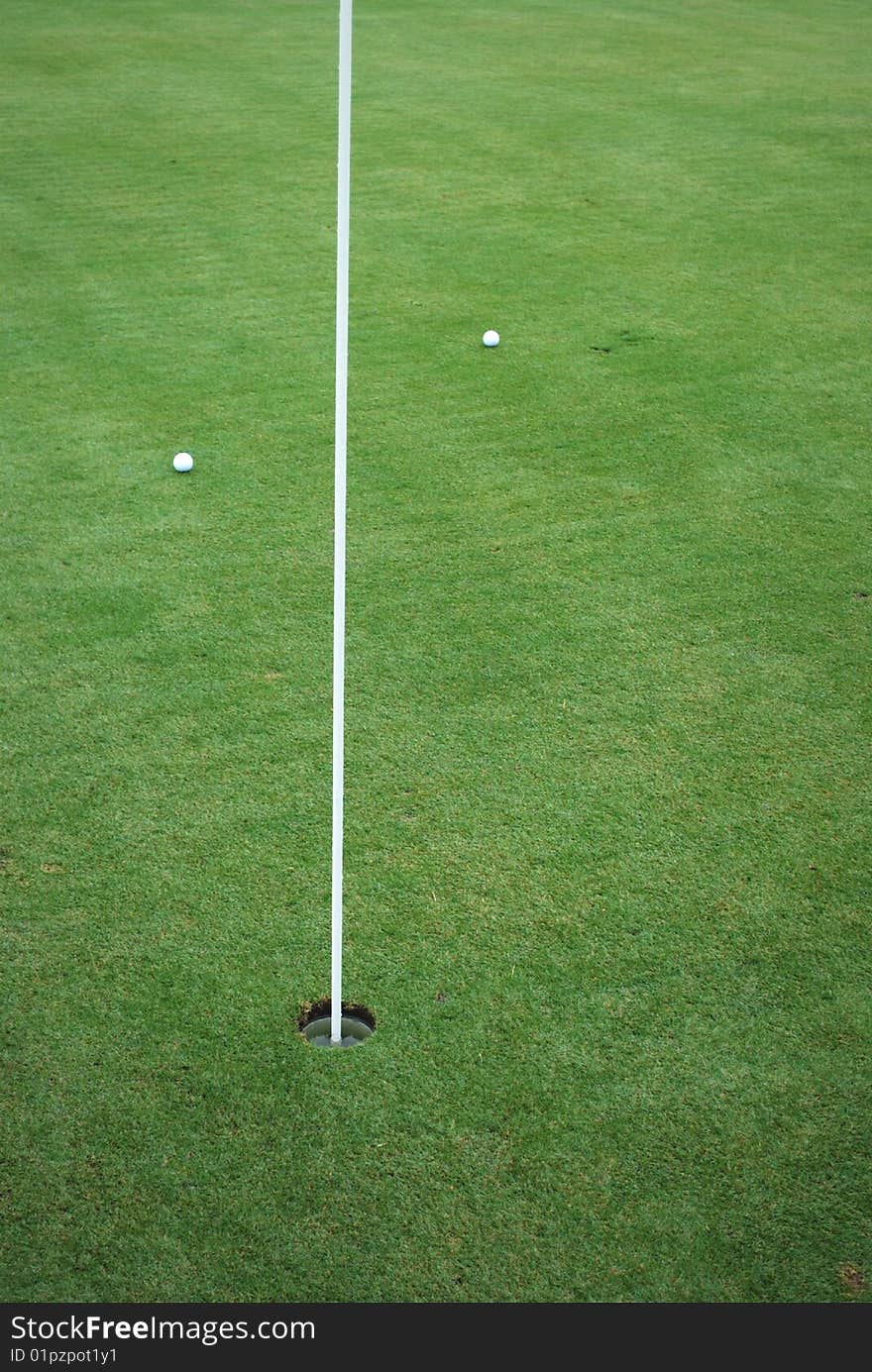 Golfballs on the green putters up close to the pin. Golfballs on the green putters up close to the pin