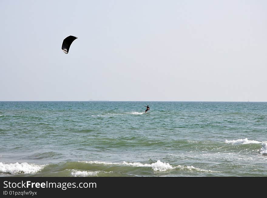 Kitesurfer in black and the sea