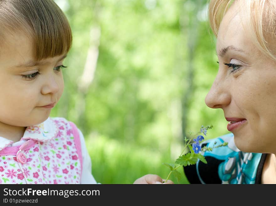 Mother and daughter with flower outdoor in Summer