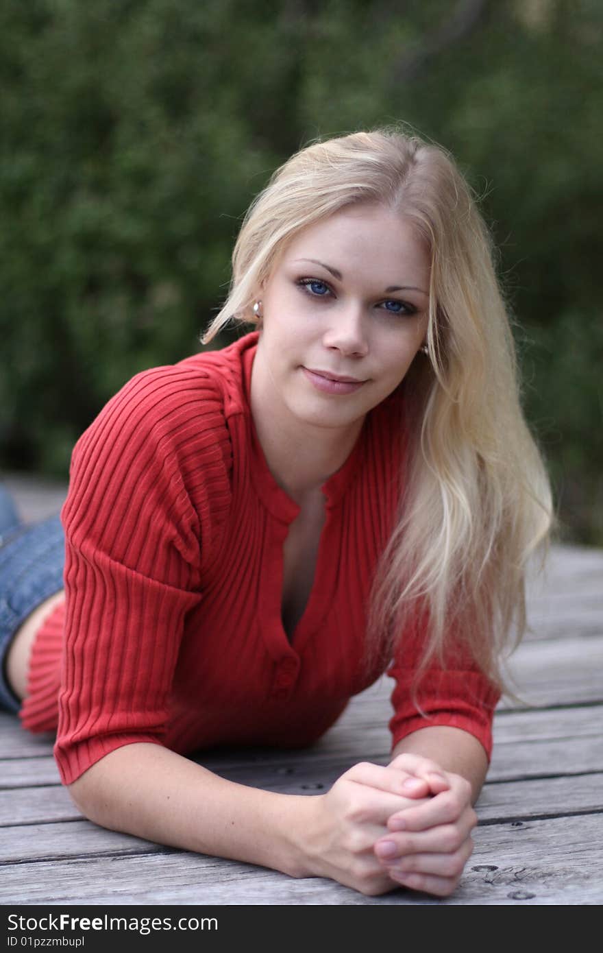 Young blonde woman leaning on wooden slats with head tilted slightly. Young blonde woman leaning on wooden slats with head tilted slightly