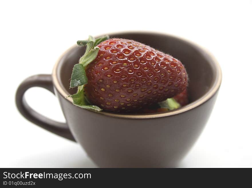 Brown coffee cup full of strawberries on a white background. Brown coffee cup full of strawberries on a white background