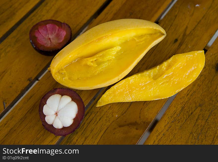 Cut tropical fruits on a wooden little table