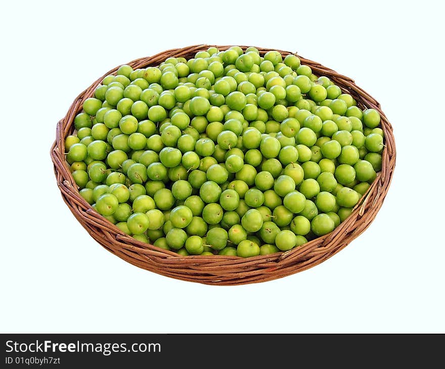 Lots of green plums in a basket, isolated on white background