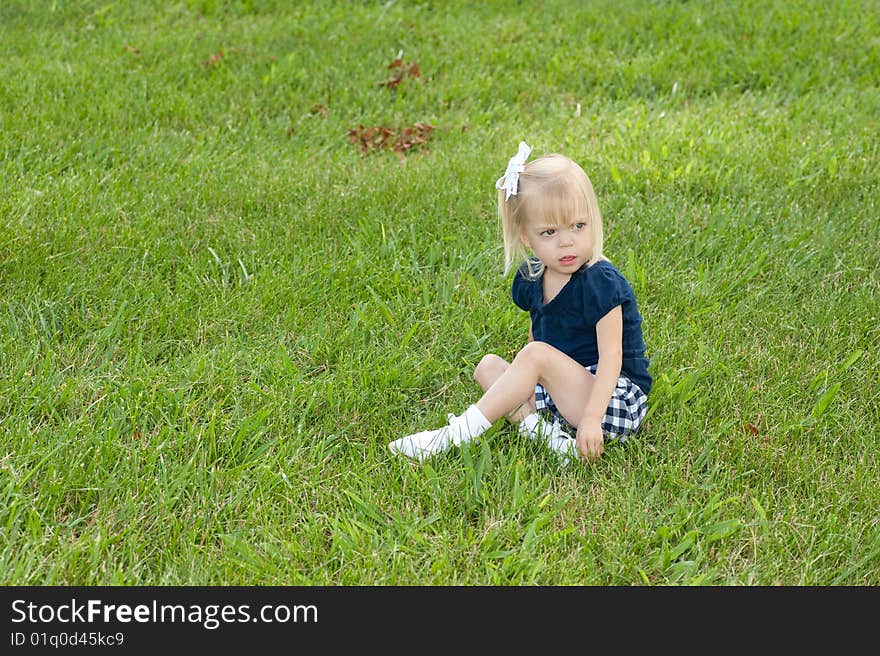 One blond girl sitting in grass. One blond girl sitting in grass