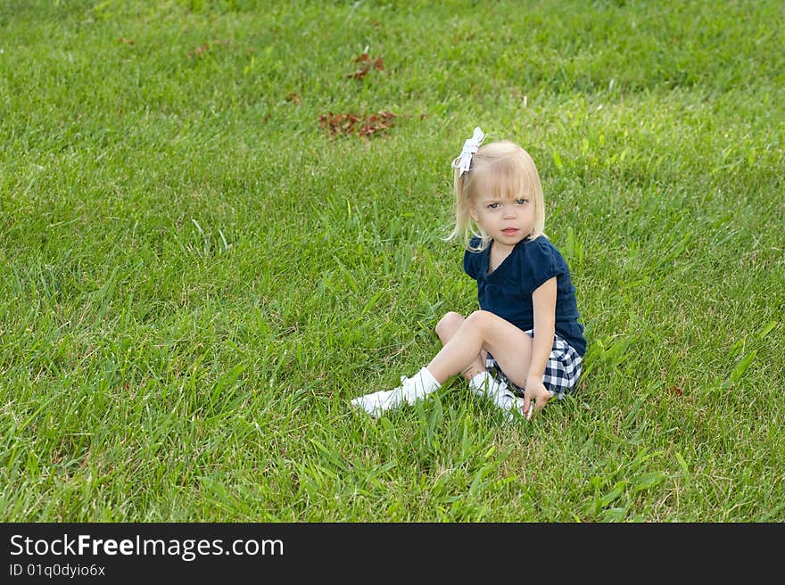 One blond girl sitting in grass. One blond girl sitting in grass