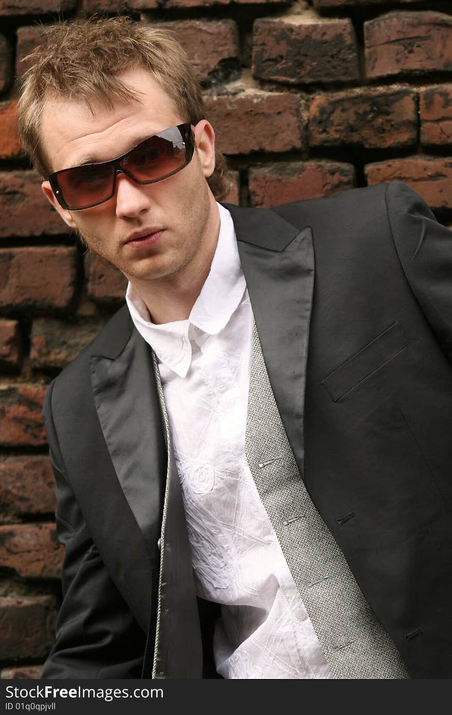 Man in sunglasses posing at the brick wall. Man in sunglasses posing at the brick wall