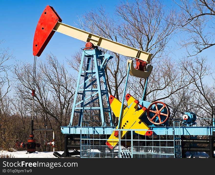 Oil pump at winter with trees at bacground