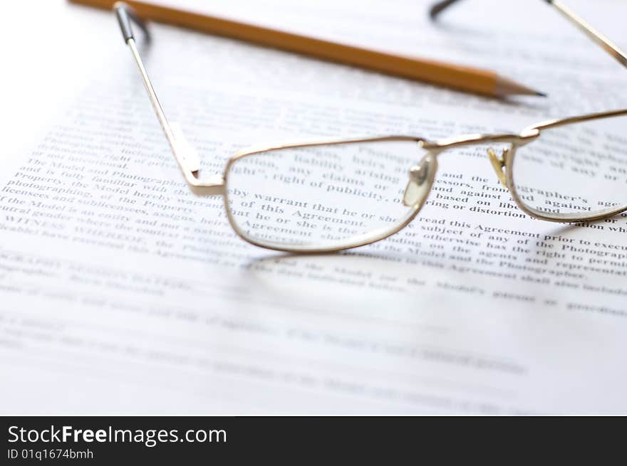 Close-up of document, eyeglasses and pencil.