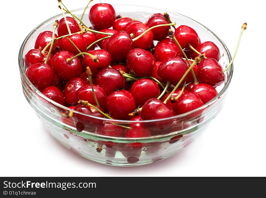 Red-ripe cherry in glass bowl on white background