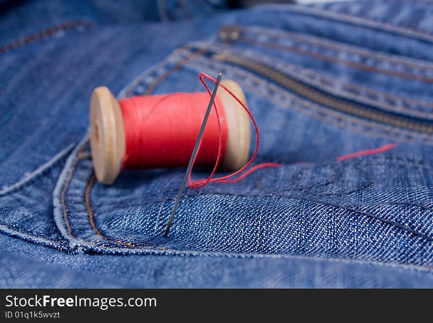 Needle with read thread on jeans.