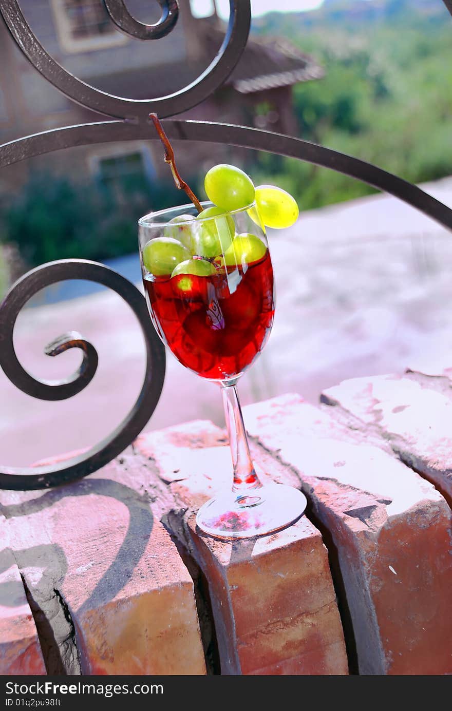 Red wine glass with grape over brick fence. Red wine glass with grape over brick fence