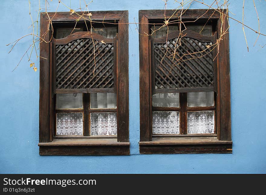 Two old wooden windows and blue adobe wall. Two old wooden windows and blue adobe wall