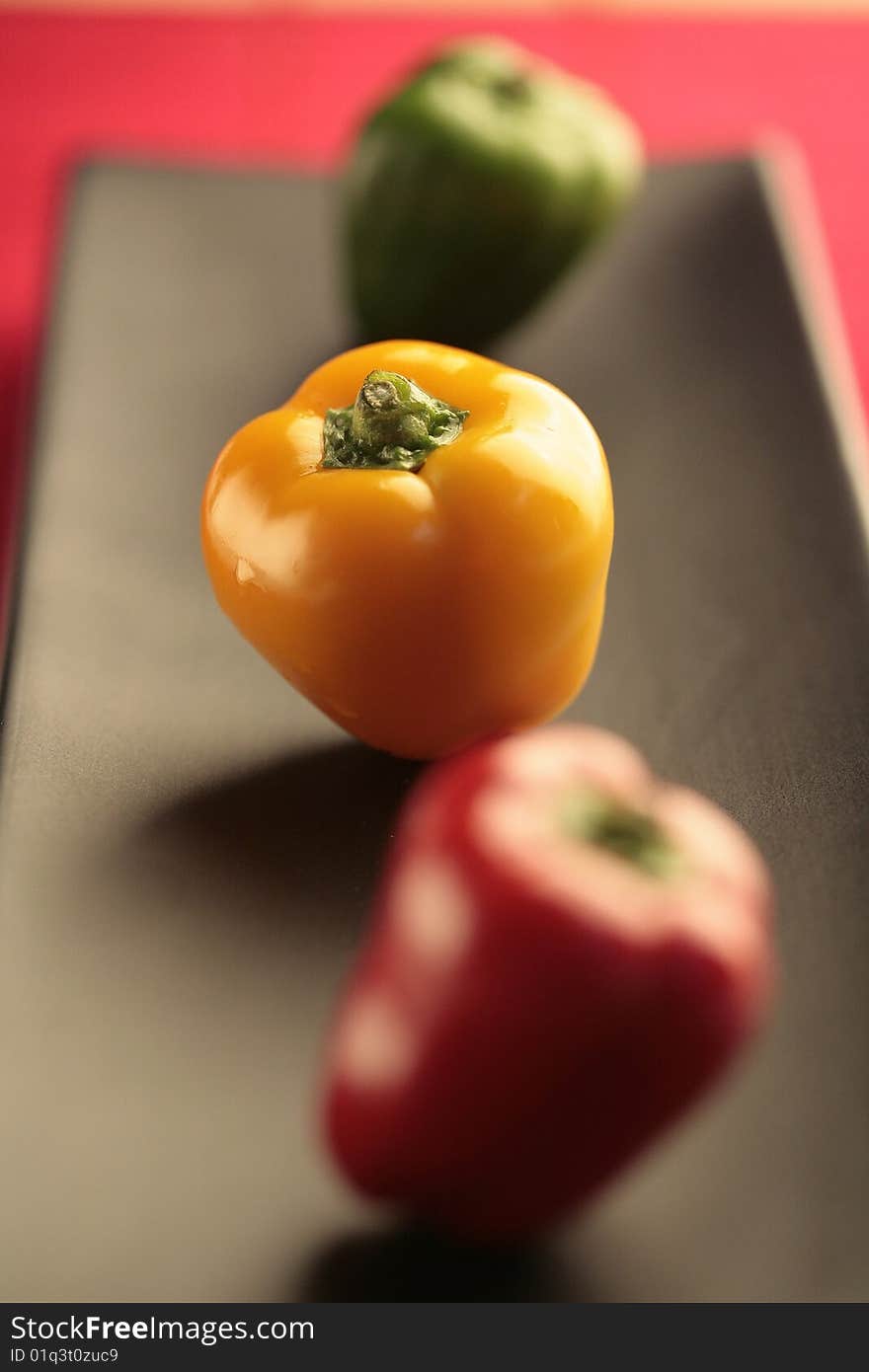 Closeup colored peppers on black plate