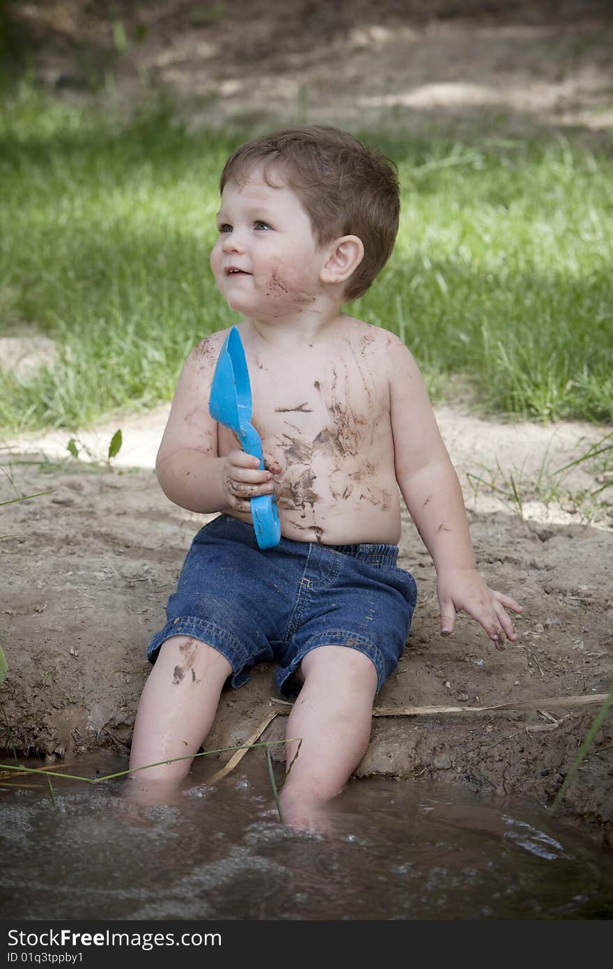 Little boy with muddy face and blue shovel