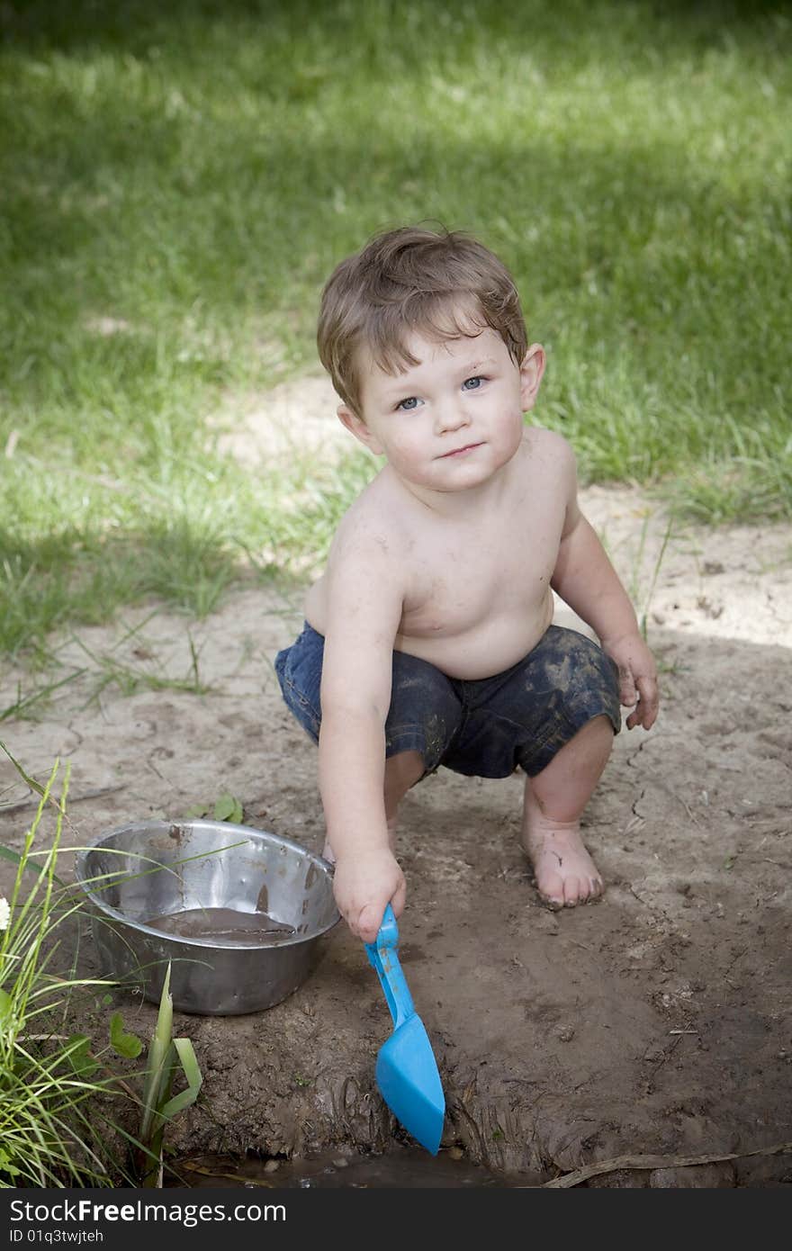 Little boy with muddy face and blue shovel