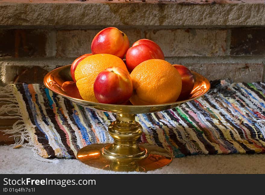 A copper vase with oranges and nectarines, standing on the floor. A copper vase with oranges and nectarines, standing on the floor