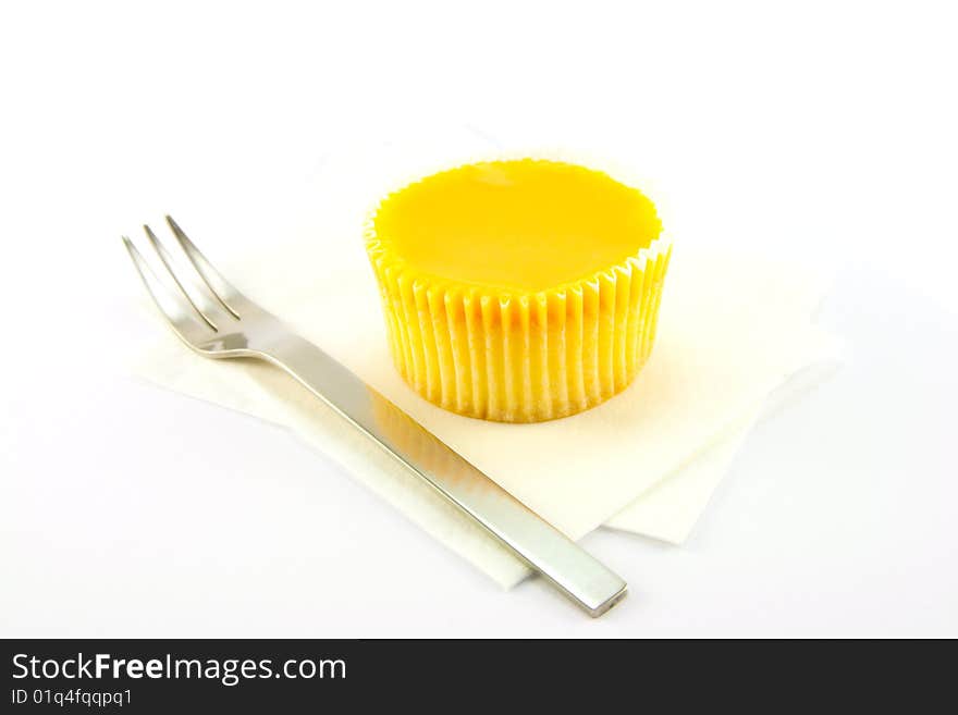 Delicious looking cup cake resting on two white napkins with a fork on a plain background