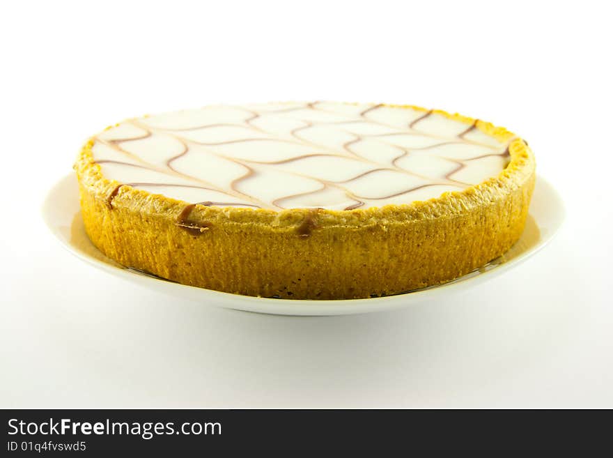 Delicious looking iced bakewell tart on a white plate with a plain background